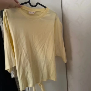 Gul knyt-topp från nelly  - Säljer en ljusgul topp från Weekday med knyt i midjan. Toppen har rund halsringning,  är tillverkad i tunn bomull som ger en luftig känsla. Perfekt för dig som gillar en enkel men ändå trendig look.knappt använd ! Pris kan diskuteras. Den är storlek L men är  passar  mig som har M 