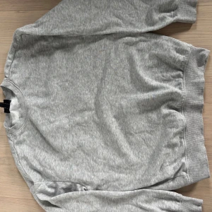 Grå loose fit sweatshirt från H&M - Enkel och stilren grå sweatshirt från H&M i loose fit-modell. Tröjan har rund halsringning, ribbade muddar vid ärmslut och nederkant samt långa ärmar. Perfekt för en chill och avslappnad look.