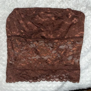 Brun spets tubtopp - Säljer en brun tubtopp i genombruten spets med blommigt mönster. 