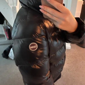 Svart pufferjacka från Colmar - Säljer en svart snygg glansig jacka från Colmar, med hög krage utan huva. Säljer då jag tröttnat på den, inga defekter, går att justera nere vid midjan, så passar både S/M. Pris kan diskuteras🤎 