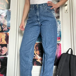 80-tals jeans - Snygga 80-tals jeans med blommiga detaljer på sidan. Lite små på mig som har 36 så skulle nog tro att dessa passa bäst på någon med 34. Jag kan mötas upp i Uddevalla centrum, annars fraktar jag gärna. Köparen står för frakten. (Står ej för postens slarv) katt finns i hemmet. 