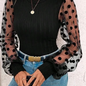 Svart ribbad topp med prickiga ärmar - Snygg svart ribbad topp med transparenta långärmade ärmar i mesh och stora svarta prickar. Ärmarna är puffiga och avslutas med breda muddar. Perfekt för dig som vill sticka ut med coola detaljer.