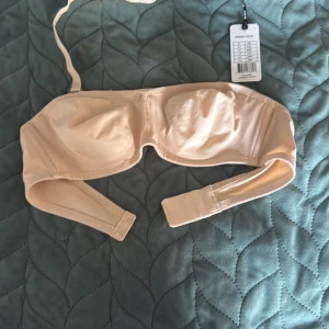 Beige bikiniöverdel 75B med bygel - Snygg beige bikiniöverdel från Accordi i storlek 75B. Modellen har bygel, justerbara axelband och knäppning bak. Tillverkad i ett slätt och stretchigt material som sitter bekvämt och ger bra stöd. Perfekt för strandhäng eller poolparty.