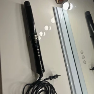Remington Digital Curling Wand - Remington digital locktång med LCD-display och justerbar temperatur upp till 210°C. Elegant svart design med blommönster. Sladd och knappar i gott skick, inga synliga defekter eller slitage. Perfekt för att skapa vackra lockar snabbt och enkelt. 32mm tjock locktång🌸🌼