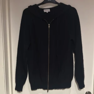 Mörkblå Zip hoodie i kashmir från Davida - Stilig mörkblå hoodie från Davida i kashmir. Tröjan har dragkedja framtill, huva och långa ärmar. Perfekt för dig som gillar en stilren och enkel look med lyxig känsla. Passar dig som vill ha något både bekvämt och snyggt.