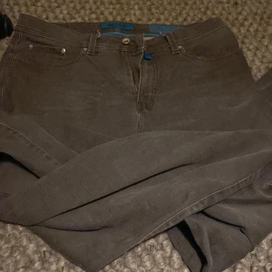 Grå Pierre Cardin Future Flex jeans - Snygga grå jeans från Pierre Cardin Future Flex med klassisk femficksdesign och blå detaljer på insidan. Jeansen har rak passform och är tillverkade i stretchigt bomullsmaterial för extra komfort. Perfekta för dig som gillar stilrena och bekväma byxor.