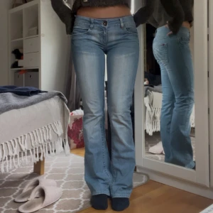 Ljusblå bootcut jeans från Replay - Snygga ljusblå jeans från Only med bootcut passform och klassiska femficksdetaljer. Jeansen har låg midja och är tillverkade i mjukt denimtyg med lätt slitning framtill och bak. Perfekta för dig som gillar en avslappnad men trendig look. Storlek 28/34