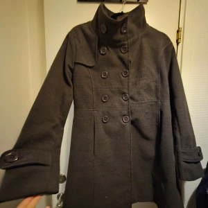 Brun kappa - Brun kappa knälängd. Vet inte vilket märke, perfekt för höst/vinter. Alla knappar finns och inga fläckar, luktar inget. Djurfritt hem. 