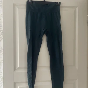 Mörkgröna seamless leggings - Snygga mörkgröna leggings med hög midja och ribbad linning. De är sömlösa och har en tight passform som sitter skönt mot kroppen. Perfekta för träning eller chill dagar. Materialet är stretchigt och följsamt.