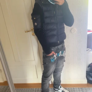 Mörkblå cardigan från Moncler - Säljer en mörkblå cardigan från Moncler med quiltad design och dragkedja framtill. Västen har en snygg huva och ett Moncler-märke på ärmen. Skick 10/10 helt ny säljer den då för att den har blivit för liten. Vid fler bilder eller frågor skriv privat. Passar mellan M och S och pris går att diskuteras 