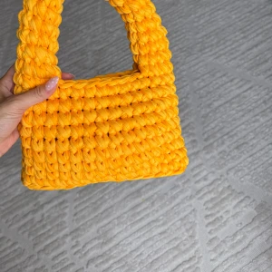 Gul stickad handväska med chunky look - Handmade Yellow Crochet Bag - Brand New, Never Used Add a pop of color to your wardrobe with this vibrant, handmade yellow crochet bag. Crafted with care and attention to detail, this unique accessory is the perfect blend of style and functionality. Features: Color: Bright, eye-catching yellow that’s sure to stand out. Material: Soft, durable crochet fabric that’s lightweight yet sturdy. Size: Compact but spacious enough for your essentials, such as your phone, wallet, and keys. Design: The stru