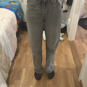 Grå raka jeans från 157 - Säljer ett par grå jeans från 157 med rak passform och hög midja. Jeansen har klassisk femficksdesign, dragkedja och knapp framtill. Materialet är robust denim i bomull och färgen är snyggt tvättad grå. Perfekta för en chill och stilren look.