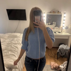 Ljusblå stickad tröja Vero Moda - Supersöt ljusblå stickad tröja från Vero Moda med puffiga korta ärmar och ribbad halsringning. Tröjan är mjuk och skönt material. 