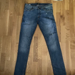 Slim jeans från Jack & Jones - Snygga blå jeans från Jack & Jones i modellen Slim/Glenn. De har en slim passform med klassisk femficksdesign och subtila slitningar för en cool look. Storlek 30w det är i mycket bra skick. Skriv om du har några frågor!