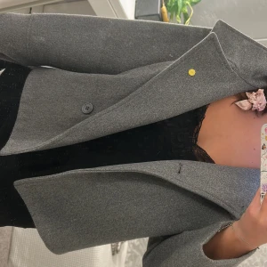 Grå kappa från Gina Tricot - Snygg grå kappa från Gina Tricot i klassisk modell, endast använt några gånger och perfekt nu till hösten! Den sitter mer som en M så man får plats med stickad tröja osv under! Köpte för 600kr!❣️