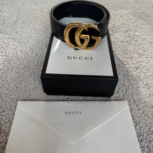 Mäns svart Gucci skärp - Säljer ett klassiskt svart Gucci-bälte i äkta skinn med den ikoniska dubbla GG-spännet i guld. Bältet är stilrent och brett, perfekt för att lyfta vilken outfit som helst. Kommer med originalbox. Kvitto finns!!