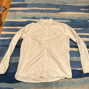 Vit skjorta från GANT  - Klassisk vit skjorta från GANT med broderad logga på bröstet. Skjortan har lång ärm, knappar framtill och button down-krage. Perfekt för dig som gillar stilrena och tidlösa plagg. Pris kan diskuteras.