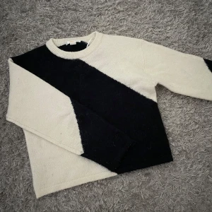 Svartvit stickad tröja från Gina Tricot - Cool stickad tröja från Gina Tricot i storlek 134/140. Tröjan är vit med en bred diagonal svart rand som går över både fram- och baksidan. Rund halsringning och långa ärmar. Perfekt för dig som gillar kontraster och enkel stil.