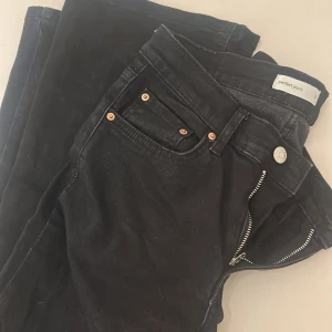 Svarta jeans från Perfect Jeans - Säljer ett par svarta jeans från Perfect Jeans med klassisk femficksdesign, silverfärgad knapp och dragkedja. Jeansen har raka ben och snygga kopparfärgade nitar vid fickorna. Perfekta till sneakers eller boots.