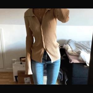 Beige ribbad kofta  - Snygg beige ribbad kofta med lång ärm och v-ringning. Storlek 32 men passar 34-36 då den är stretchig och mjuk. Knappt använd överhuvudtaget.