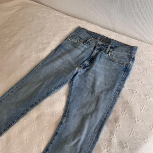 Acne ljusblå raka jeans 31/34 - Ljusblå jeans från Acne Jeans i rak modell. Jeansen är tillverkade i 100% bomull och har snygga slitningar och lagningar baktill för en cool vintagekänsla. Två professionella lagningar på bakdelen. Riktigt feta