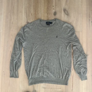 Grå tröja från Polo Ralph Lauren - Snygg grå tröja från Polo Ralph Lauren i slim fit-modell. Tillverkad i mjuk pima bomull och har rund halsringning samt den klassiska broderade loggan på bröstet. 