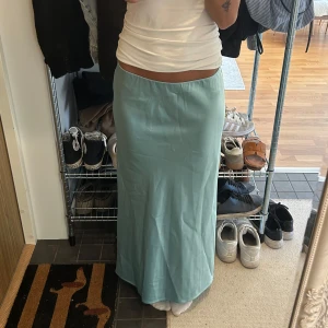 Ljusblå långkjol i bomull - Säljer en stilren ljusblå långkjol med rak passform. Kjolen är tillverkad i mjukt bomullsmaterial och har en enkel design utan synliga detaljer eller mönster. Perfekt för dig som gillar minimalistisk och clean stil.