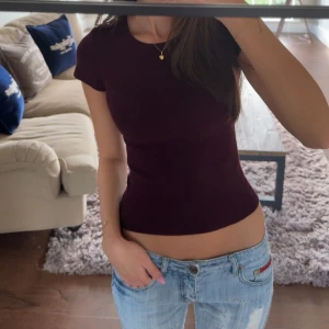 Mörklila/röd tight topp med knappar - Säljer en mörklila/ röd topp med tight passform och korta ärmar. Toppen har rund halsringning och dekorativa guldfärgade knappar på ena axeln. Helt ny💕