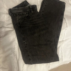 Svarta Jack&jones jeans 29/32 - Säljer ett par svarta jeans med rak passform. Jeansen har klassisk femficksdesign och är i ett tvättat svart tyg som ger en cool, lite sliten look. Perfekta för dig som gillar en enkel och stilren vibe.