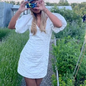 Vit kort klänning med puffärmar - Superfin vit kort klänning med strukturmönster och puffiga korta ärmar. Djup v-ringning och figurnära passform som ger en trendig look. Perfekt för student eller sommarens alla tillfällen. Materialet känns lätt och luftigt. Den va storlek 36 från början men har sytt in den i midjan och gjort kortare så skulle säga att den är storlek 34 nu.
