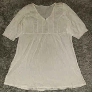 Vit kortklänning från KappAhl - Supersöt vit topp från KappAhl i storlek M. Toppen har v-ringning, broderade detaljer upptill och halvkort ärm. Tillverkad i mjukt bomullstyg som känns luftigt och skönt. Perfekt för varma dagar och har en enkel, fräsch look.