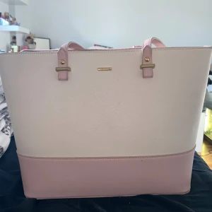 Ljusrosa och beige axelväska Lovevook - Snygg axelväska från Lovevook i ljusrosa och beige med guldiga detaljer. Väskan har stilren design, dragkedja upptill och flera fack inuti för smart organisering. Perfekt storlek för att få plats med allt du behöver och matchar lätt till olika outfits.