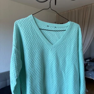 Mintgrön/turkos stickad v-ringad tröja - Superfin mintgrön stickad tröja med v-ringning och lång ärm. Tröjan har ett diskret strukturerat mönster och är perfekt för dig som gillar en fräsch och chill look. 