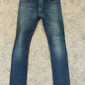Blå skinny jeans från Nudie Jeans - Snygga blå jeans från Nudie Jeans. Jeansen har en smal passform och är tillverkade i mjukt jeanstyg som sitter tajt längs benen. Perfekt för dig som gillar en modern och stilren look.