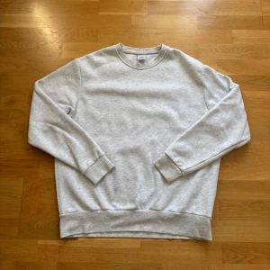 Ljusgrå sweatshirt från Zara - En stilren ljusgrå sweatshirt från Zara med rund halsringning och ribbade muddar vid ärmslut och nederkant. Perfekt för en chill och avslappnad look. Tillverkad i mjuk bomullsblandning som känns skön mot huden.