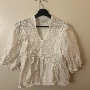 Vit broderad blus från JDY - Superfin vit blus från JDY med broderade detaljer och v-ringning. Blusen har trekvartsärmar med volangkant och knappar framtill. Använd 1 gång💕💕