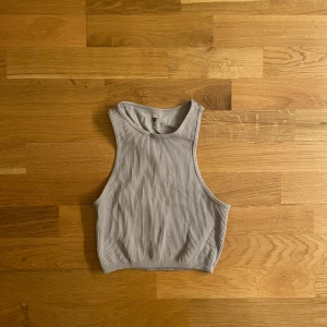 Ljuslila ribbad linnetopp - Säljer en ljuslila ribbad linnetopp. Toppen är croppad och ärmlös med hög halsringning och breda axelband. Perfekt för en trendig och avslappnad look.