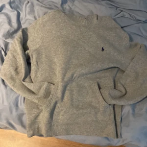 Grå Ralph lauren hoodie - Snygg Ralph lauren tröja. Utan några slitningar eller hål, Perfekt skick. Köpt för 1100kr på kidsbrandstore.se. Jag är 168 och som man ser är den lite för liten på mig. Hör av vid funderingar.
