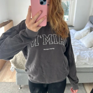 Mörkgrå AIM'N sweatshirt - Mysig mörkgrå sweatshirt från AIM'N med vit text framtill. Tröjan har rund hals, långa ärmar och ribbade muddar vid ärmslut och nederkant. Perfekt för chill dagar eller när du ska till gymmet