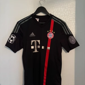 Bayern München 2014/15 Robben Champions League  - Storlek: 176 / Small. Mycket bra skick (slitet tryck på ryggen). Äkta Adidas-tröja med Champions League-patchar. Robben #10 på ryggen  Perfekt för samlare eller fans av Bayern München!