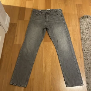 Grå loose fit jeans från Jack & Jones - Säljer ett par grå jeans från Jack & Jones i modellen Loose/Chris. Jeansen har en loose passform, raka ben och klassisk femficksdesign. Tillverkade i bomull med en snygg tvättad grå färg som ger en avslappnad vibe.