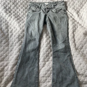 Grå bootcut jeans från Gina Tricot - Snygga grå jeans från Gina Tricot i bootcut-modell. Jeansen har klassisk femficksdesign, normal passform och är tillverkade i ett mjukt bomullsmaterial med lite stretch. Perfekta för dig som gillar en retroinspirerad look med utsvängda ben. Har en liten fläck på rumpan men går bort i tvätten.
