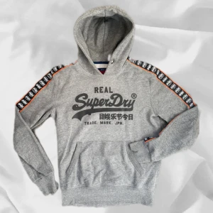 Superdry hoodie - Fet superdry hoodie i storlek Small sitter som M – enkel att matcha och skön att bära. Ett stilrent val, noggrant utvalt med omsorg av AM Clothing.  📩 Frågor? Hör gärna av dig! 📲 Följ oss här på Plick för fler uppdateringar. ♻️ Tack för att du handlar mer hållbart med AM Clothing!