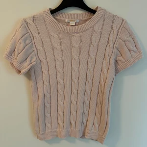 Stickad rosa tröja från Gina Tricot - Supersöt rosa stickad tröja från Gina Tricot med korta ärmar och klassiskt flätmönster. 
