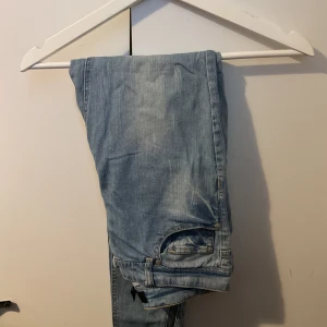 Ljusblå jeans med raka ben - Säljer ett par ljusblå jeans med klassisk femficksdesign och raka ben. Jeansen har en avslappnad passform och är tillverkade i mjukt denimtyg. Perfekta för en chill och stilren look. Kedjaslits på sidorna.