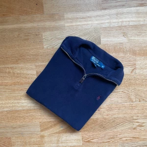 Polo Ralph Lauren Quarterzip- storlek M, Äkta  - Klassisk och tidlös halvzip-tröja från Polo Ralph Lauren i marinblå färg med den ikoniska röda loggan på bröstet. Perfekt för höst och vår – kan bäras både till vardags och lite mer uppklätt.  ✅ Storlek: M ✅ Färg: Marinblå ✅ Skick: Mycket bra, sparsamt använd ✅ Material: Bomullsblandning (bekväm och slitstark)  Nypris ca 1500–2000 kr. 