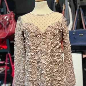 Rosa blus med 3D blommigt mönster - Supersöt rosa blus från Ida Sjöstedt med långärmade ärmar och transparent mesh upptill. Klänningen har 3D-blommor över hela tyget och prickigt mönster på meshpartiet. Perfekt för dig som vill sticka ut med romantiska detaljer och unik design.