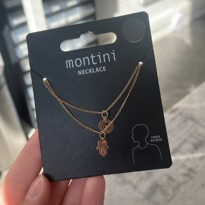 Guldigt halsband  - Snyggt guldigt halsband från Montini med två tunna kedjor och detaljerade berlocker. Kedjan är 40+8 cm. Helt oanvänd fortfarande i förpackning.