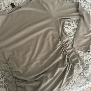 Beige långärmad topp från SHEIN Curve - Snygg beige långärmad topp från SHEIN Curve med rynkade detaljer på sidorna. Tillverkad i mjukt och stretchigt material som sitter skönt på kroppen. Perfekt för dig som gillar stilrena och trendiga plagg med en twist.