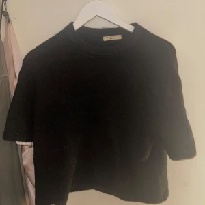 Svart stickad tröja Gina Tricot - Mysig svart stickad tröja från Gina Tricot med kort ärm och rund halsringning. Använd fåtal gånger. 